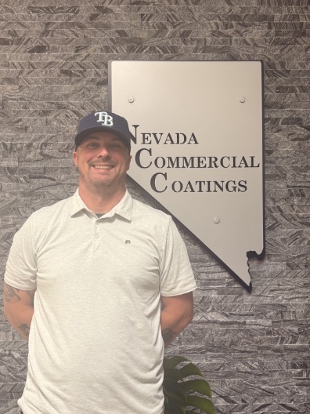Adrian next to the Nevada Commercial Coatings wall logo